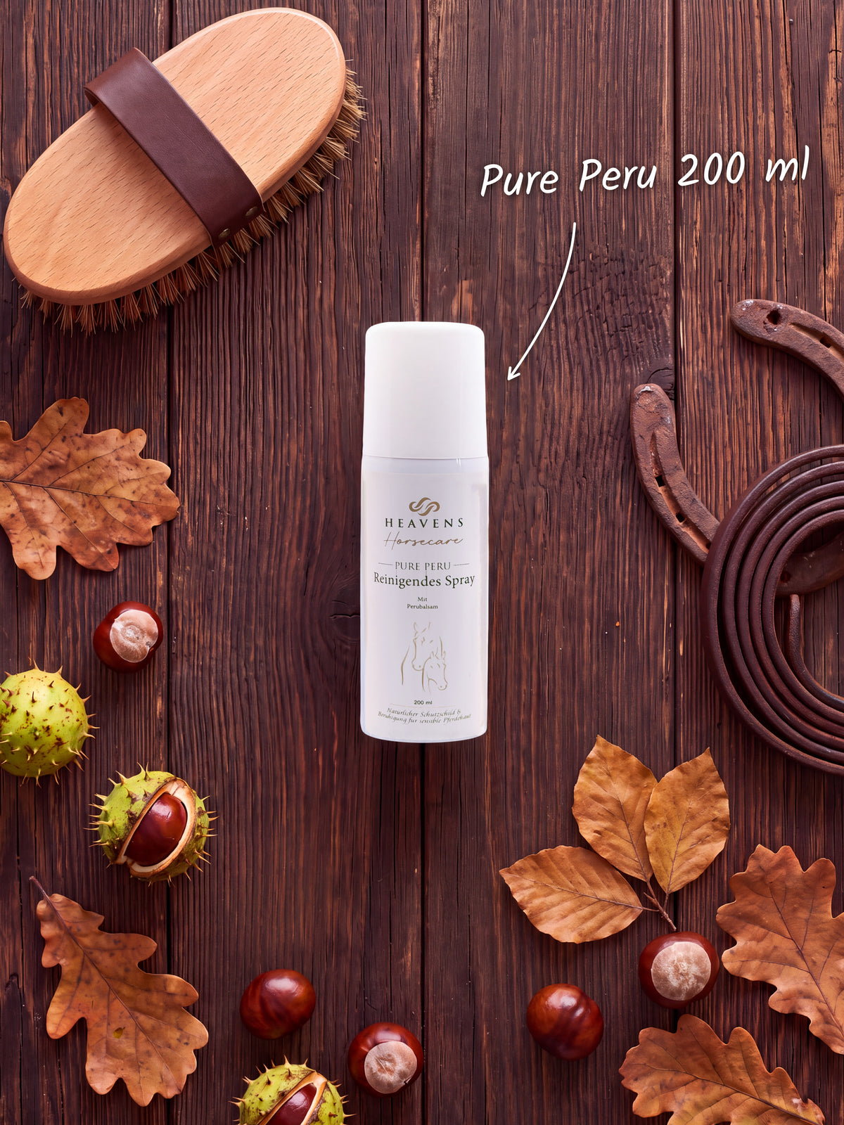 Heavens Horsecare Pure Peru Reinigendes Spray 200 ml mit Perubalsam in der Sprühdose, auf dunklem Holz neben Pferdebürste, Hufeisen und Lederstrick, dazu Kastanien und Herbstlaub