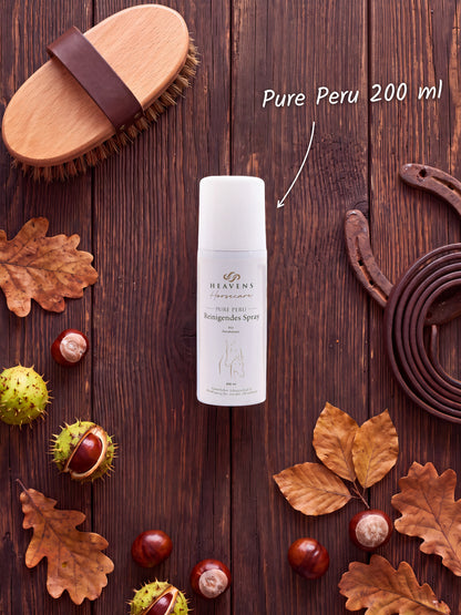 Heavens Horsecare Pure Peru Reinigendes Spray 200 ml mit Perubalsam in der Sprühdose, auf dunklem Holz neben Pferdebürste, Hufeisen und Lederstrick, dazu Kastanien und Herbstlaub