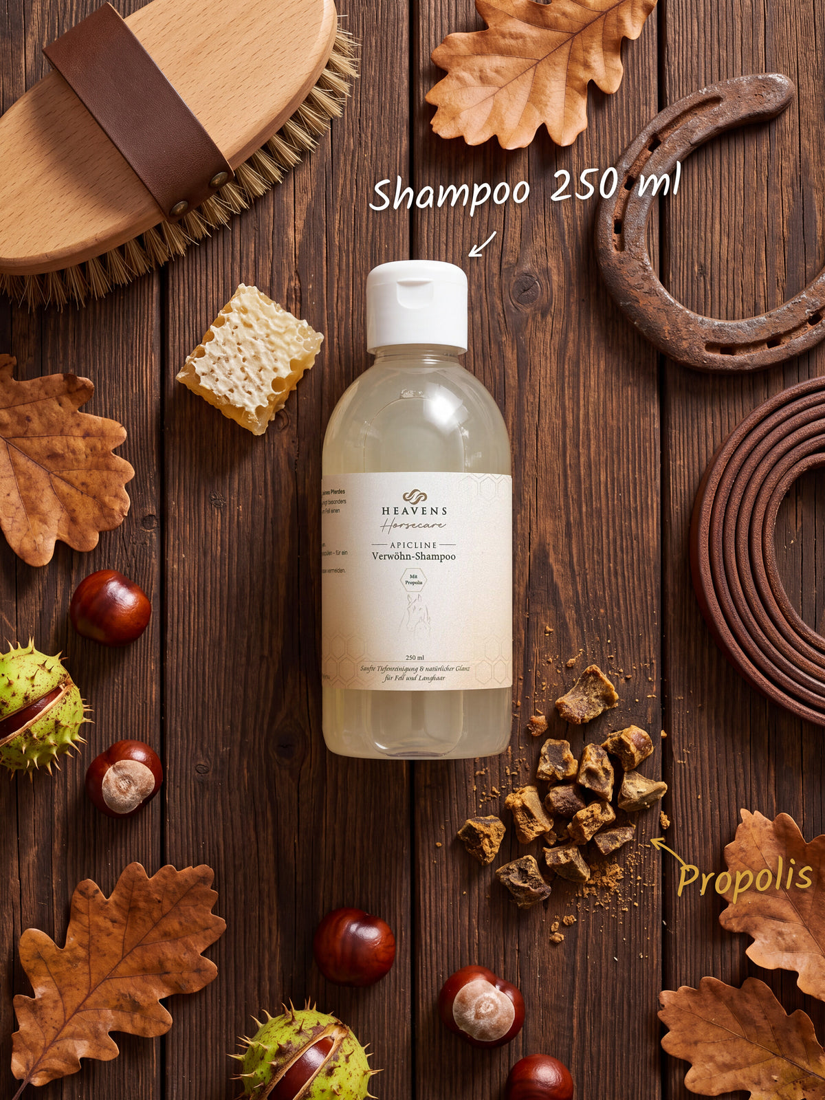 Heavens Horsecare Verwöhn-Shampoo 250 ml mit Propolis in der Flasche, auf dunklem Holz neben Pferdebürste, Hufeisen und Lederstrick, dazu Rohpropolis, eine Wabe, Kastanien und Eichenlaub